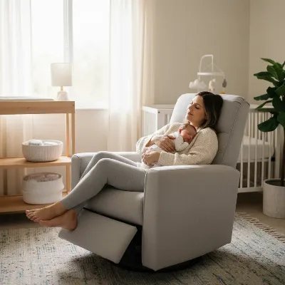 A parent gently cradling a newborn in a cozy, modern swivel glider recliner in a softly lit nursery with warm tones.
